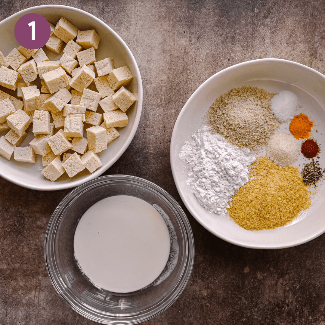 bowl of tofu cubes, bowl of buttermilk, and bowl of spices and starch for breading.