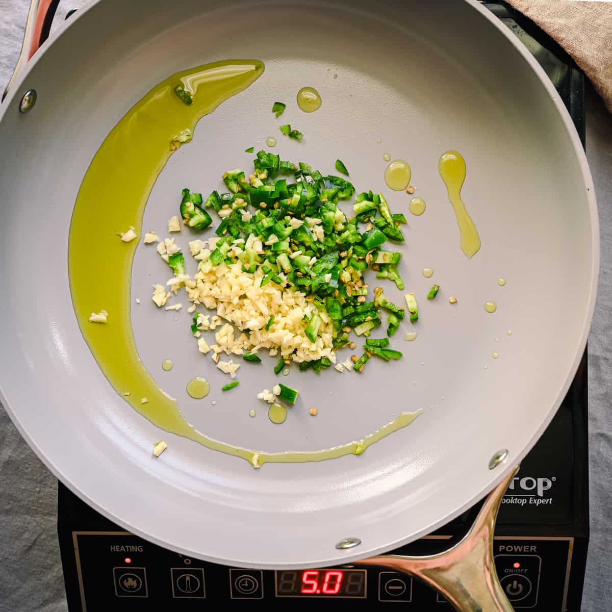 garlic and jalapenos frying in oil in frying pan