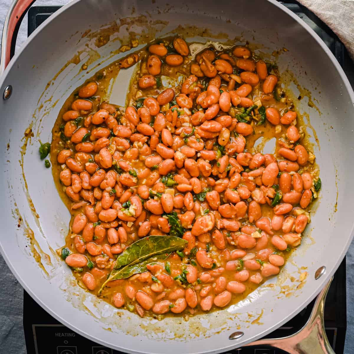 cooked pinto beans with bay leaves in frying pan