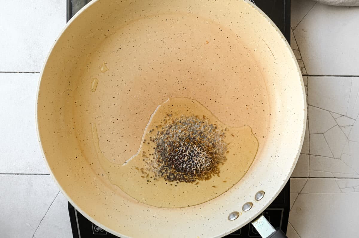 black mustard seeds and cumin seeds in oil in a frying pan