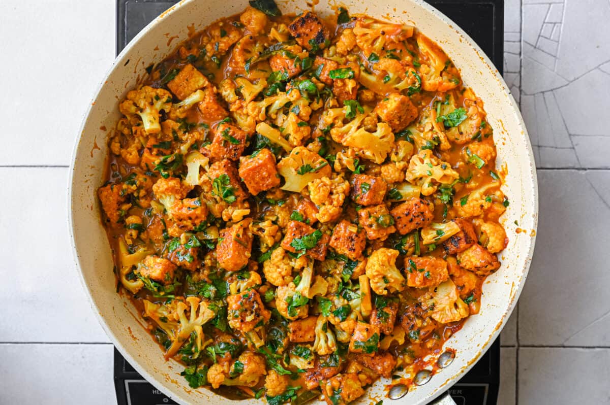 Indian spiced vegan curry with tofu and cauliflower in a frying pan
