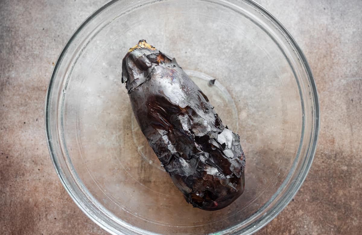 charred whole eggplant in bowl 