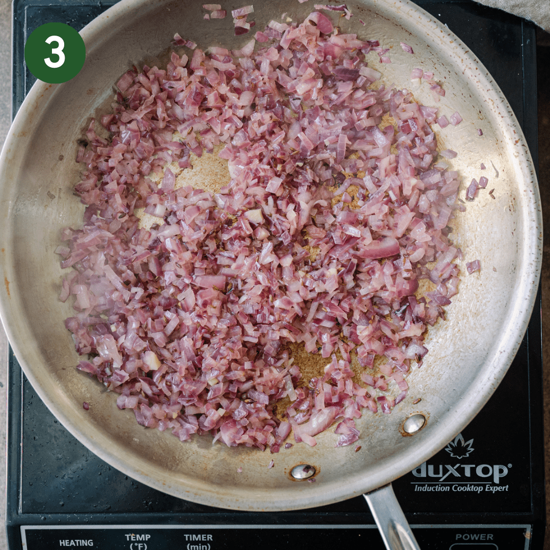 diced red onions browning in oil in a stainless steel skillet.
