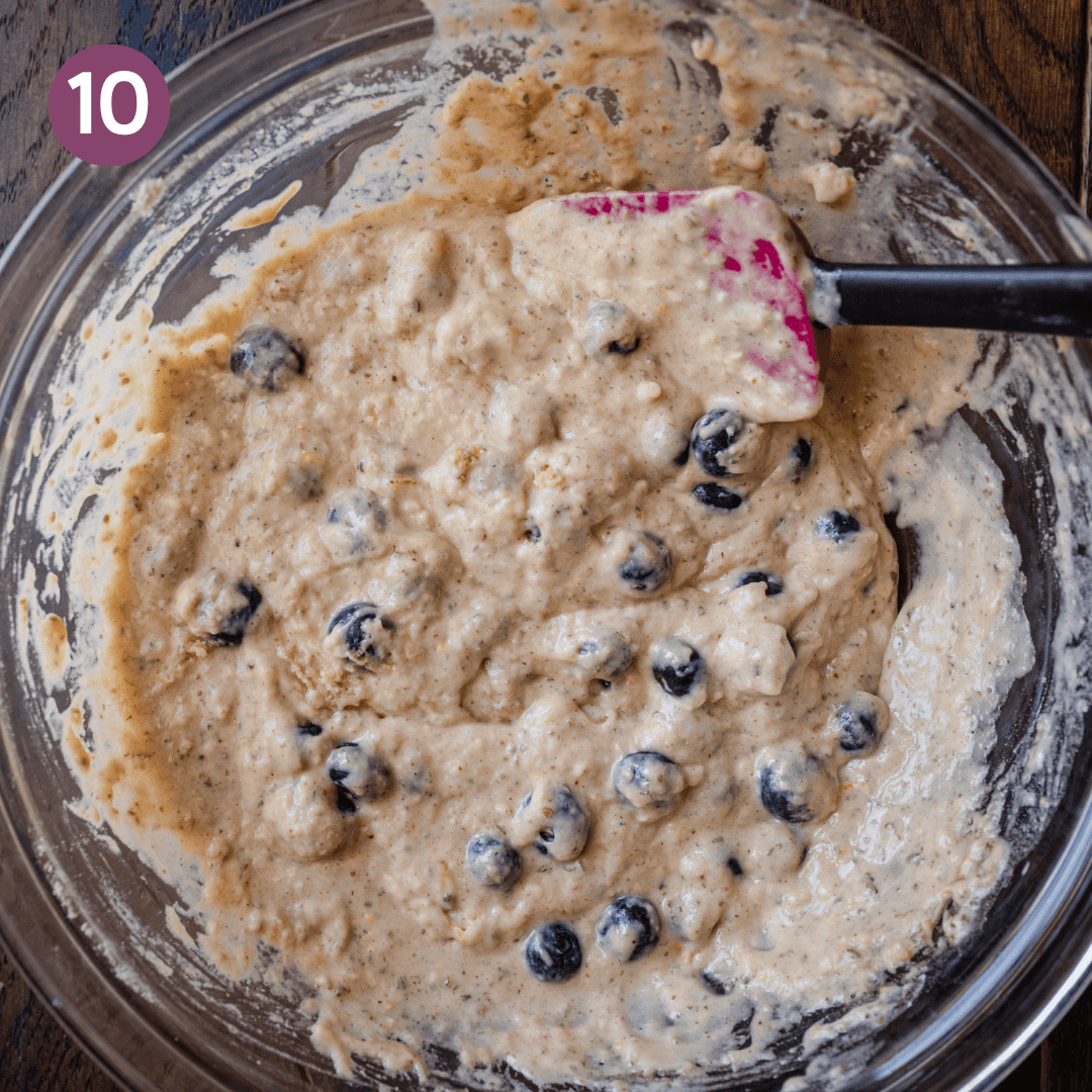 blueberries being mixed into muffin batter with a spatula.