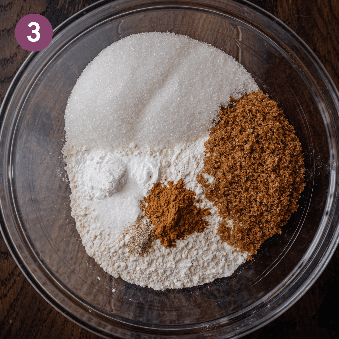 bowl of flour, sugar, spices, and baking powder in a glass bowl on wooden board.