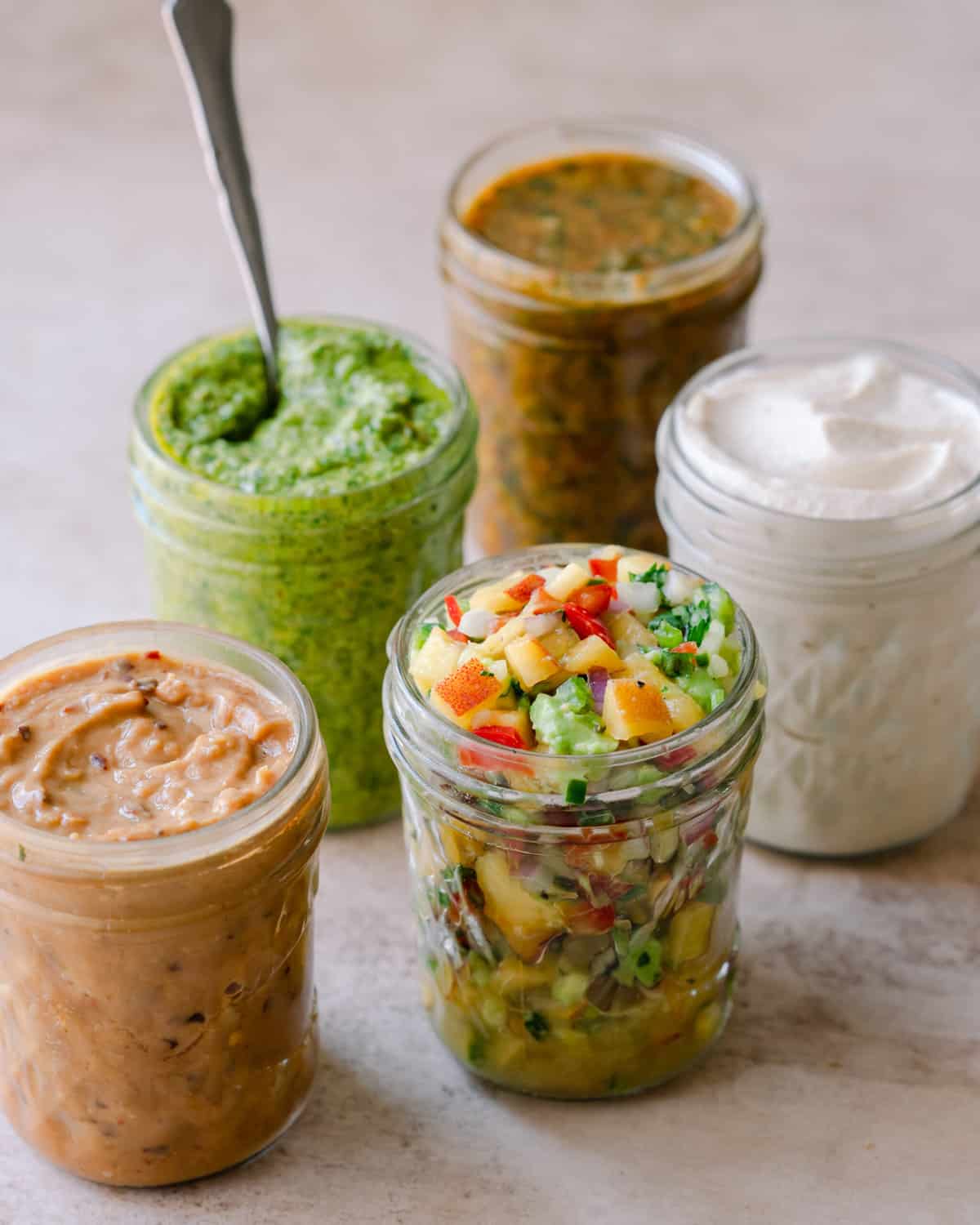 5 jars of sauces: peanut sauce, cilantro pesto, peach salsa, chipotle sauce, cashew cream.