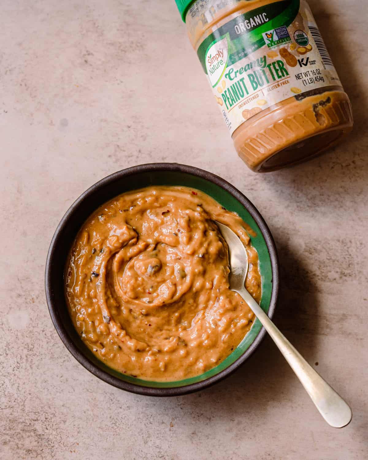 creamy and spicy peanut sauce in a small green bowl with a spoon.