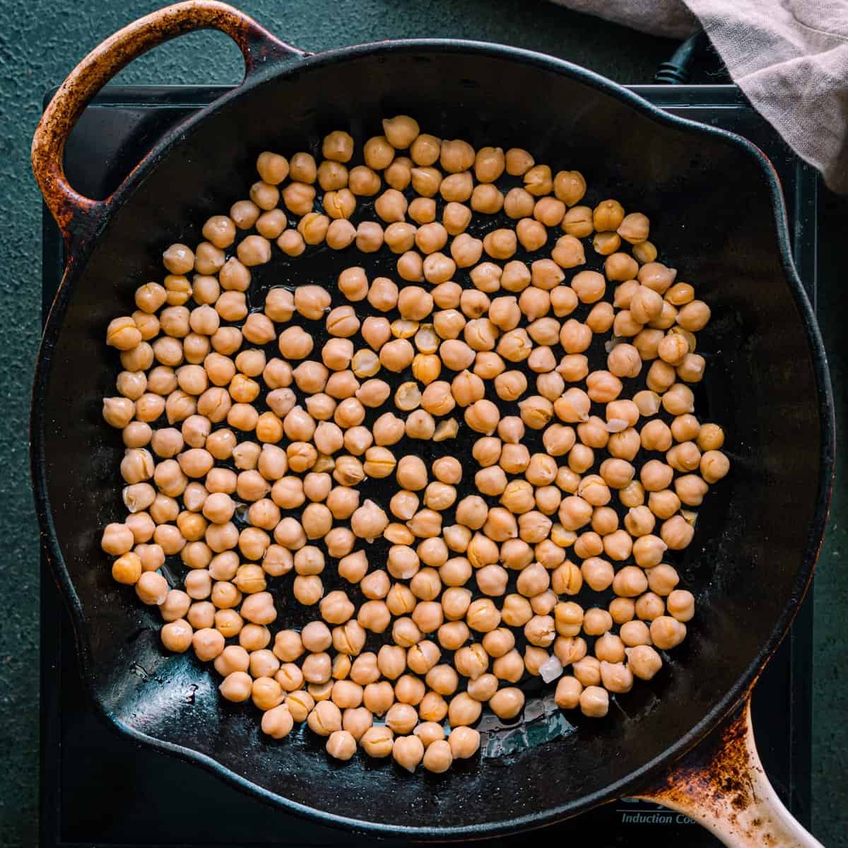chickpeas cooking in a black skillet