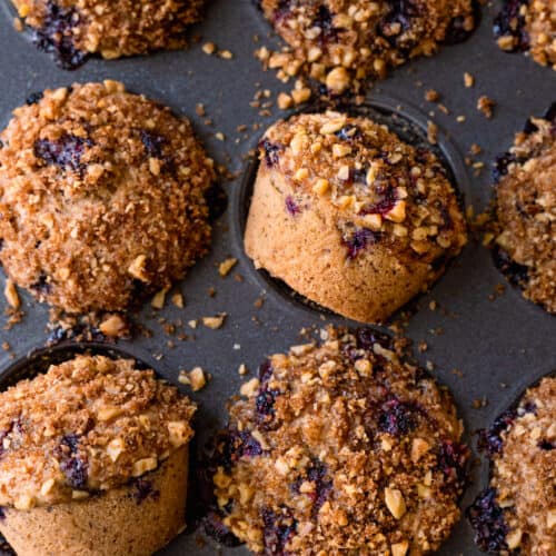 closeup of vegan blueberry muffins with walnut brown sugar crumble in muffin tin.