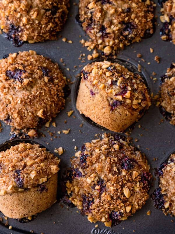 closeup of vegan blueberry muffins with walnut brown sugar crumble in muffin tin.