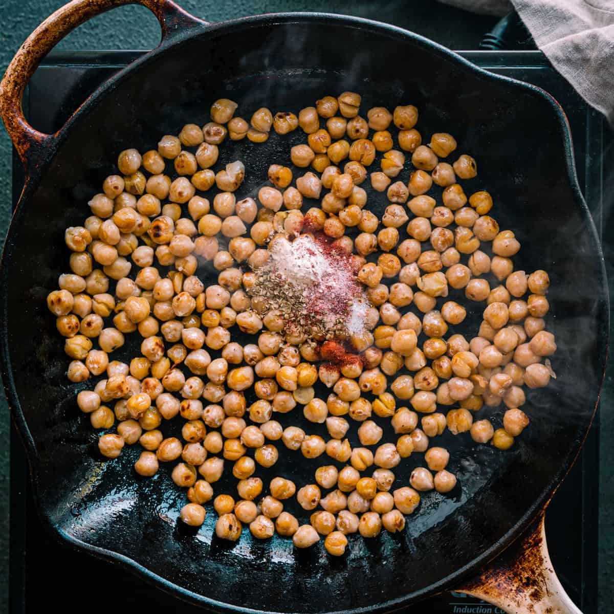 pan-frying chickpeas with spices and salt in a saute pan