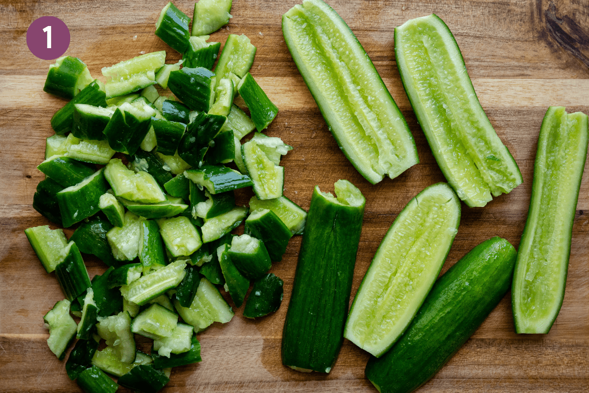 smashed cucumbers on wooden cutting board, some torn into pieces and some kept whole