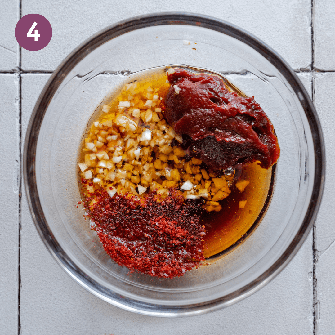 glass bowl with gochujang, gochugaru, soy sauce and ingredients for korean cucumber salad. 