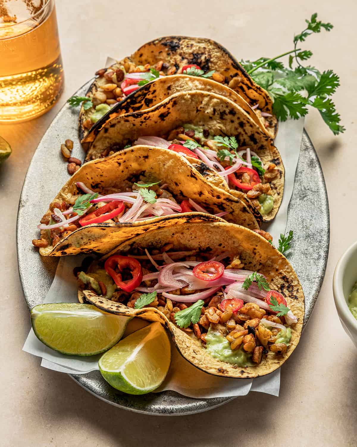 Side view of four tempeh tacos on a large plate.