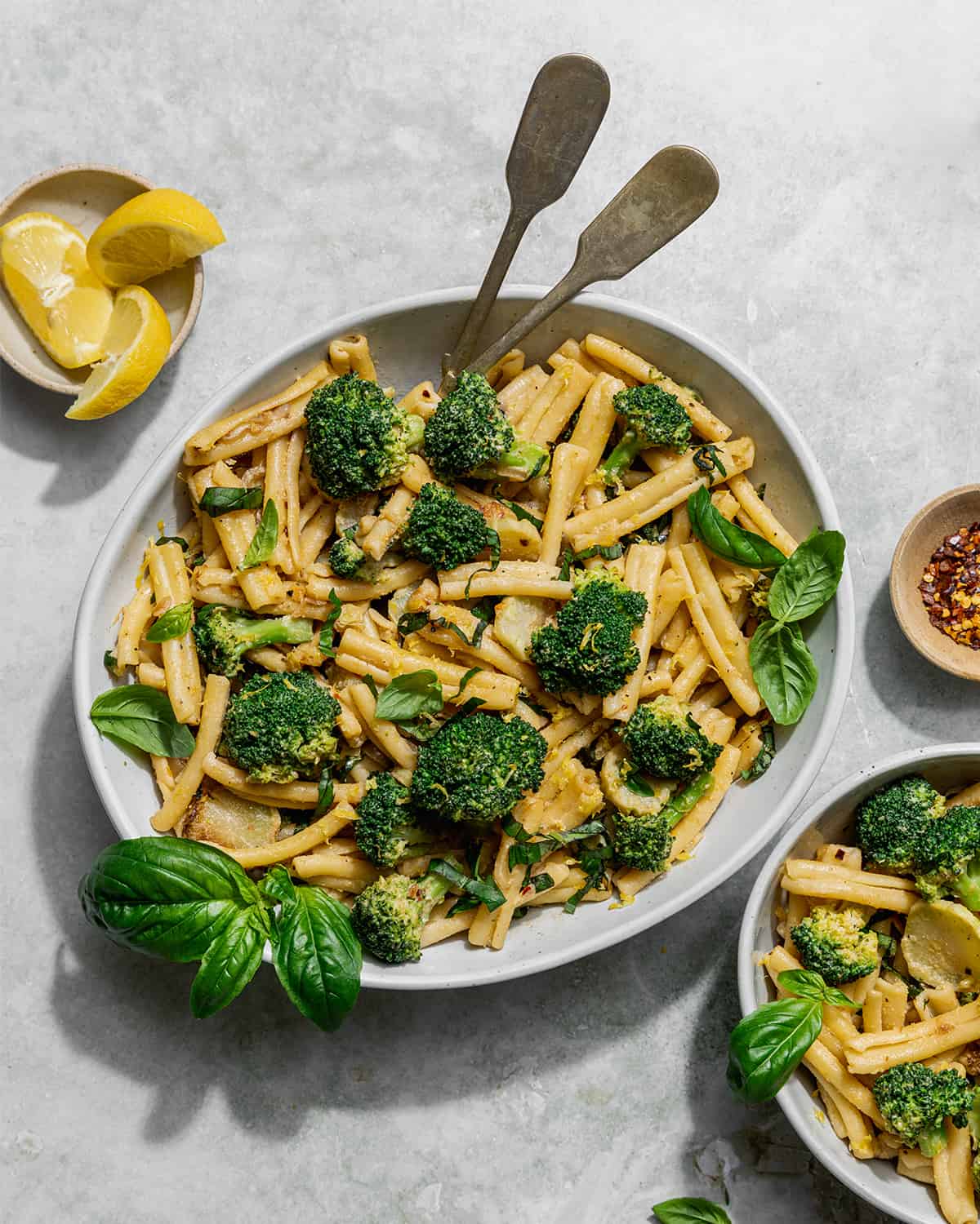 a bowl of tahini pasta and broccoli with a small bowl of pasta on the side.