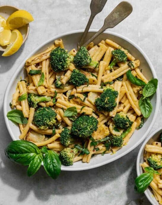 a bowl of tahini pasta and broccoli with a small bowl of pasta on the side.