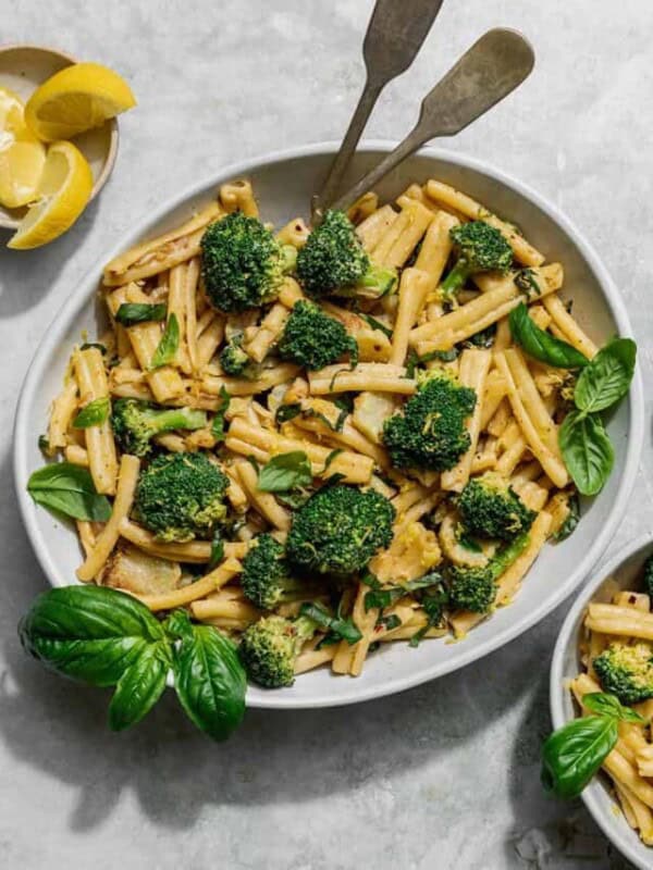 a bowl of tahini pasta and broccoli with a small bowl of pasta on the side.
