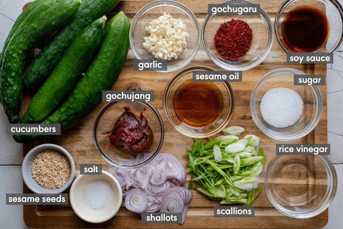 ingredients for spicy cucumber salad on wooden cutting board with ingredients labeled.