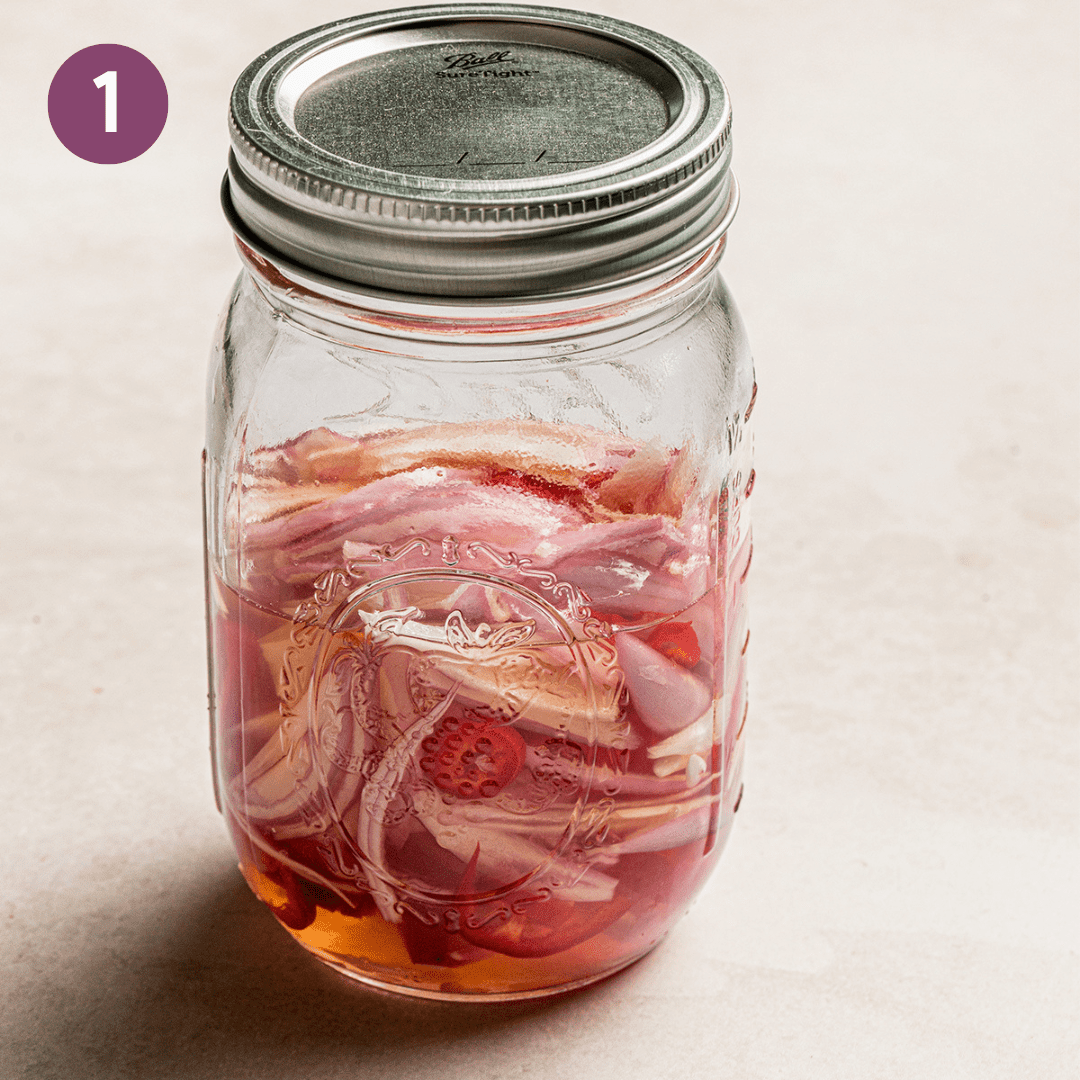 Pickled shallots and chile peppers in a small mason jar.