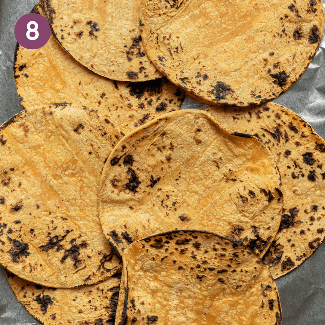 Charred tortillas piled on top of each other on a piece of tin foil.