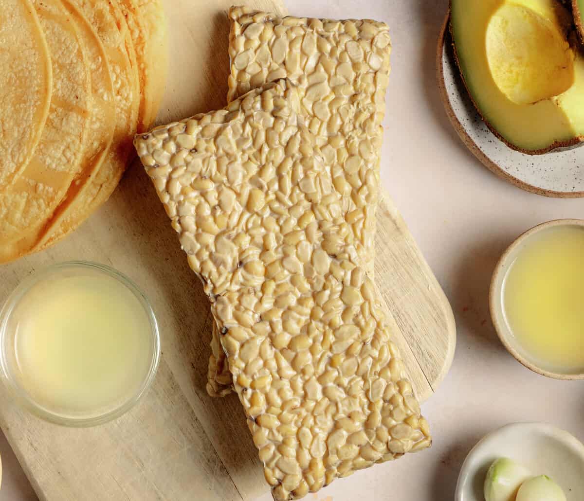 closeup photo of tempeh on a cutting board surrounded by other ingredients for tacos.