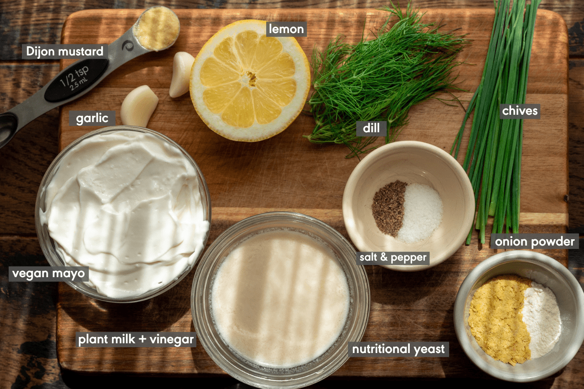 ingredients for vegan ranch dressing laid out on wooden cutting board in morning light.