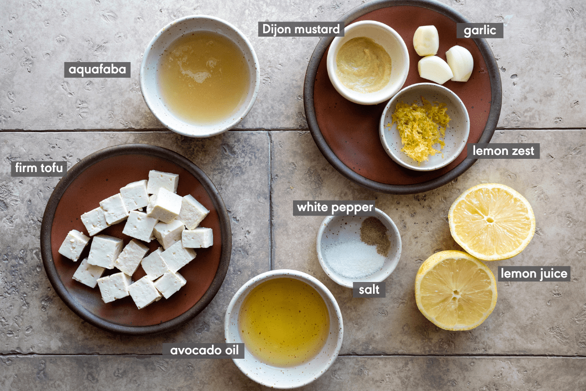 Aioli ingredients in various bowls on a cream counter. 