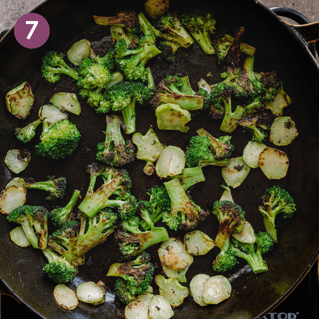 Charred broccoli in a large cast iron skillet.