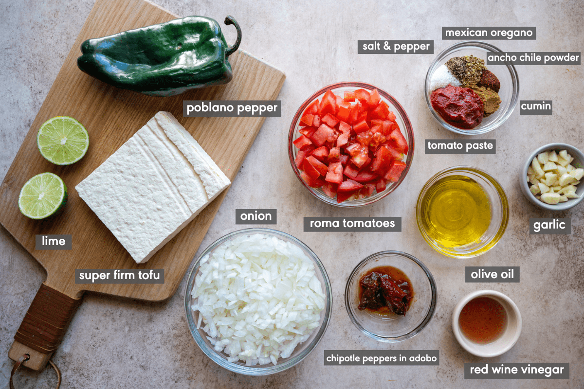 Sofritas ingredients in small glass bowls and on a wooden cutting board with ingredients labeled. 