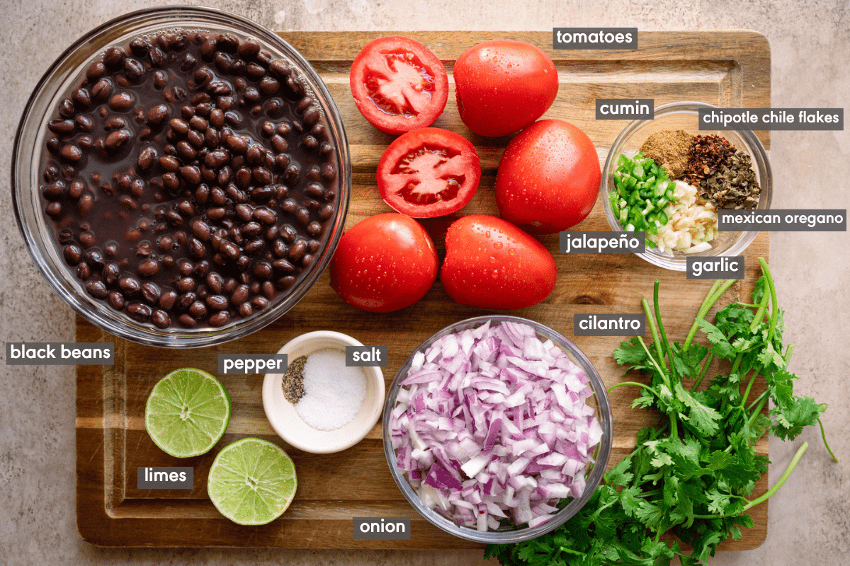 Mexican black beans ingredients laid out on a wooden cutting board.