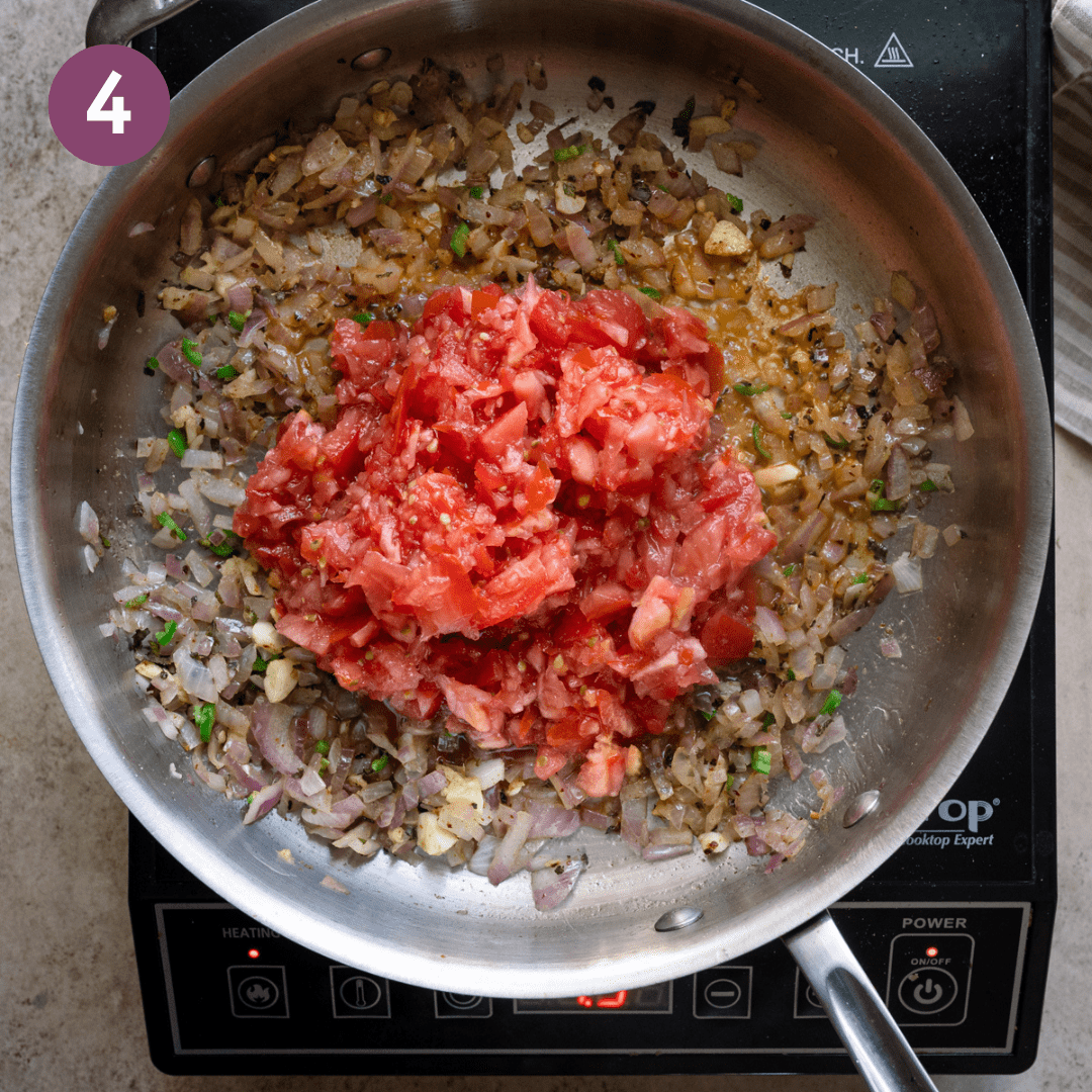 Pureed tomatoes added to aromatic and spice mixture in pan.