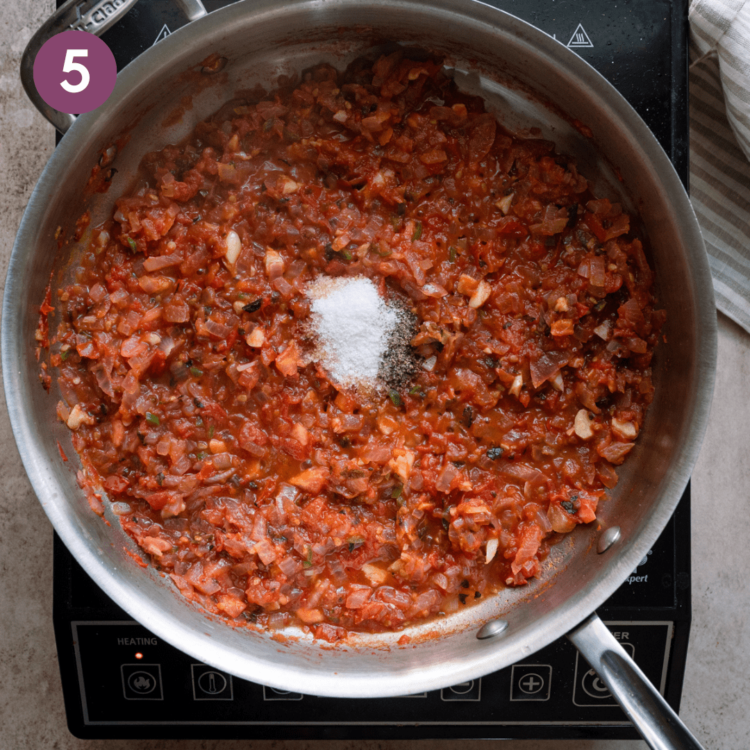 Salt and pepper added to tomato onion mixture in pan.