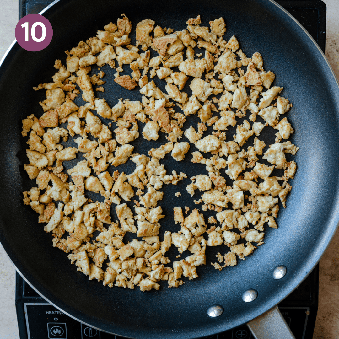 Browned tofu crumbles in a frying pan.
