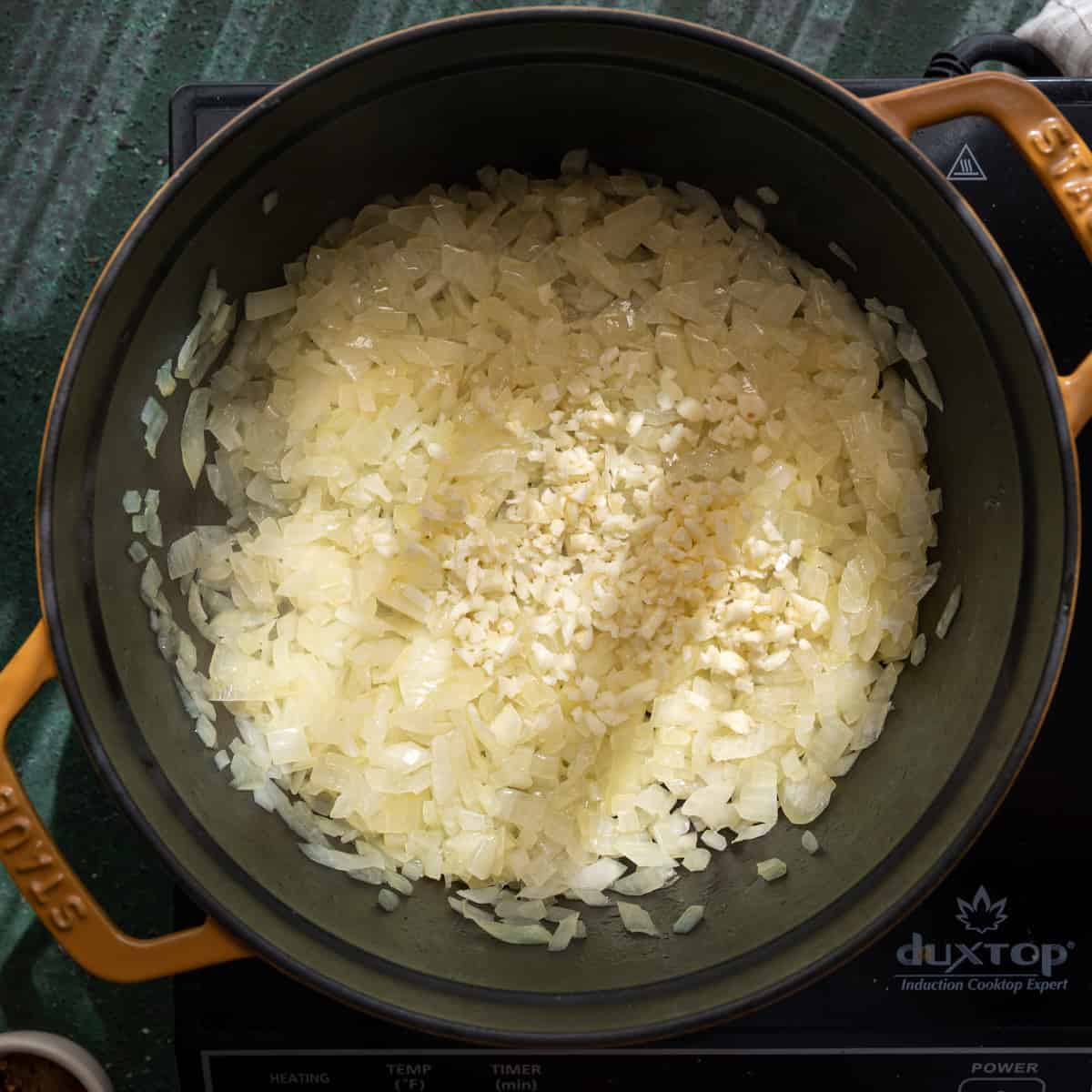 sauteed onions and garlic cooking in a dutch oven. 