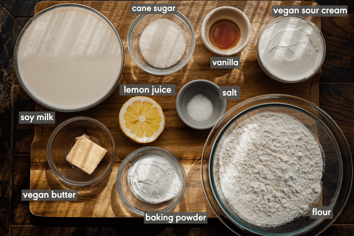 ingredients for vegan pancakes laid out on a wooden cutting board with ingredients labeled. 