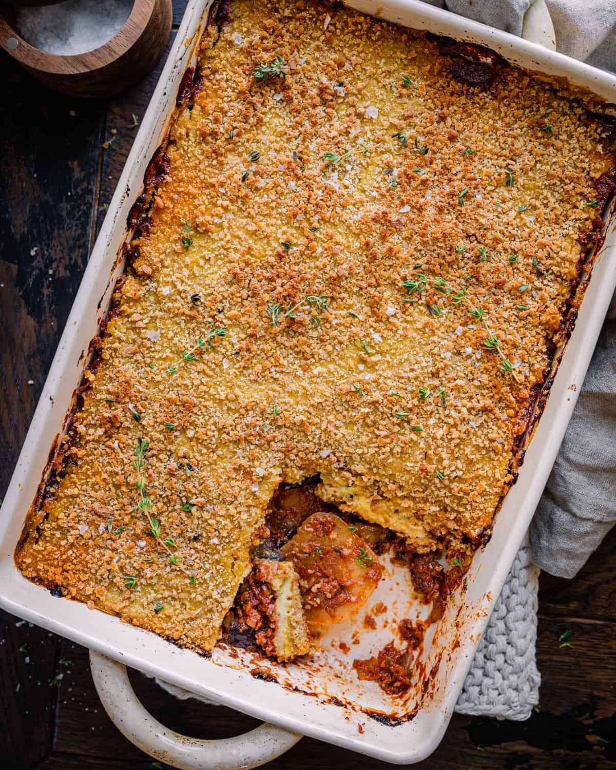 a casserole pan with vegan moussaka, with one slice cut out.