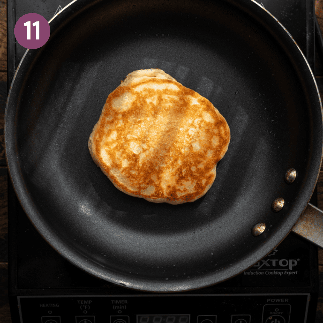 vegan pancake with golden brown exterior cooking in a black skillet.