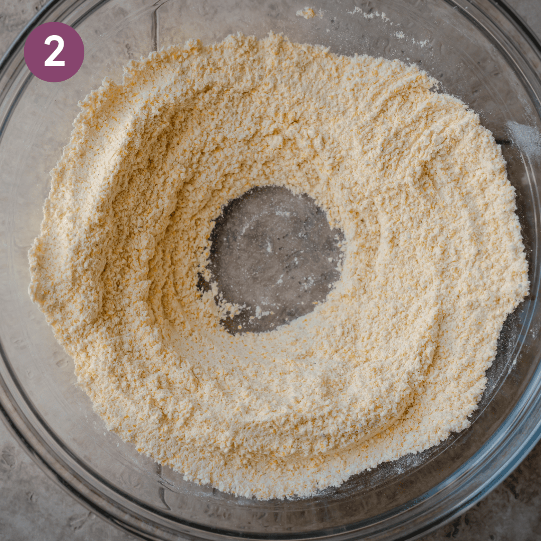 large glass bowl with cornmeal and flour mixed together with a well in the center.