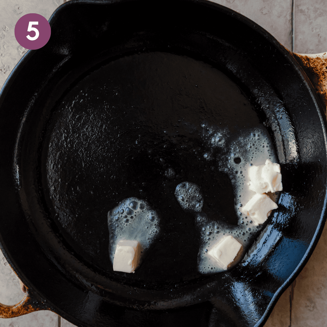 a few pieces of vegan butter melting in a cast iron skillet.