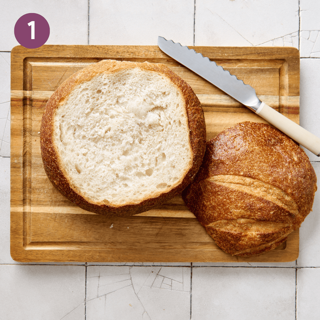 sourdough bread boule on a wooden cutting board with top sliced off.