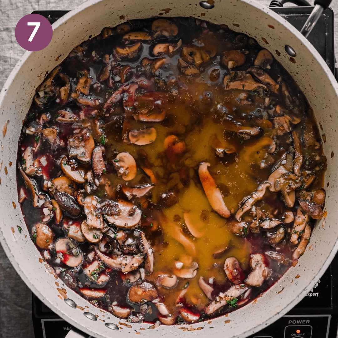 red wine and vegetable deglazing a pan of sauteed mushrooms.