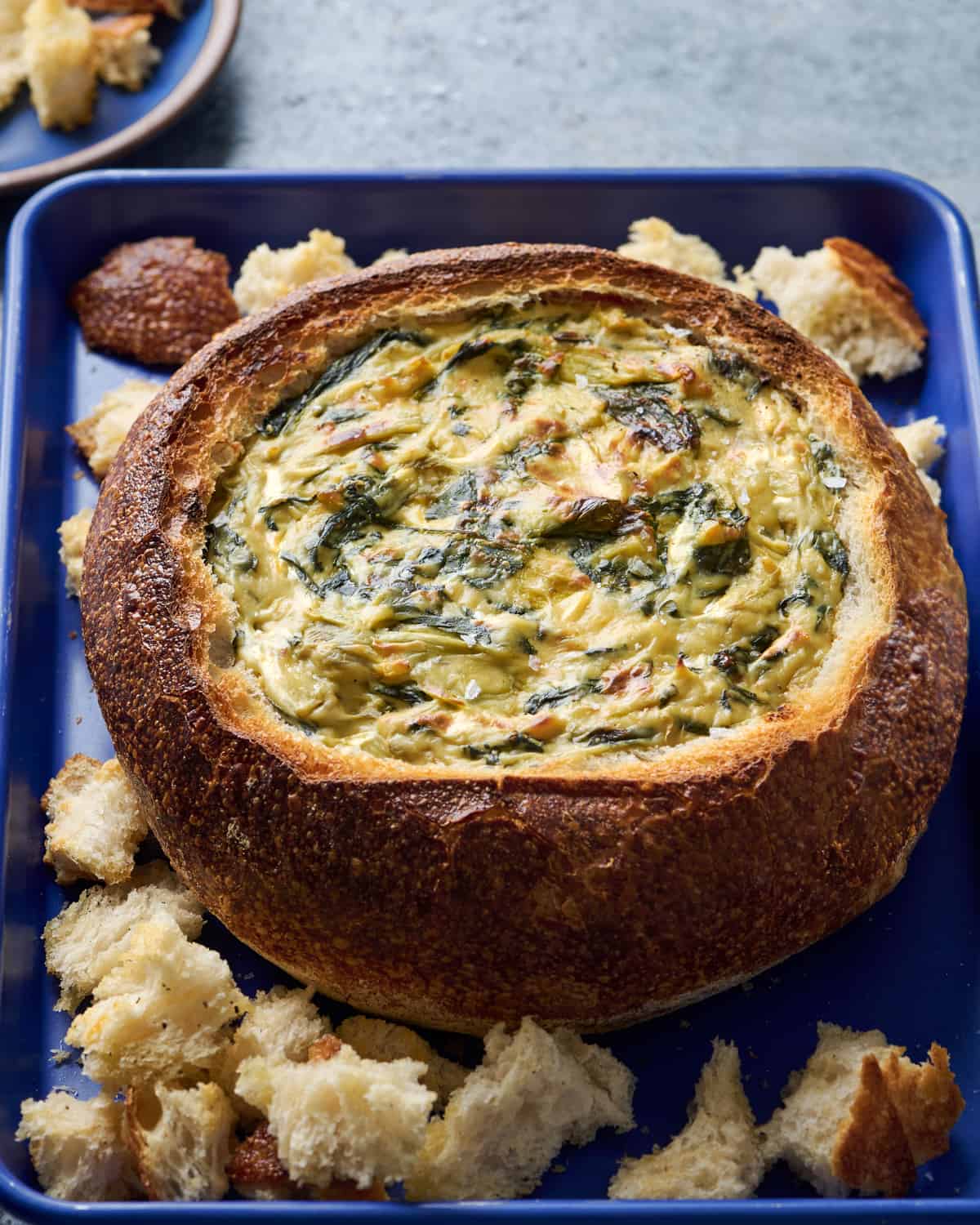 Side view of spinach artichoke dip in a bread bowl.