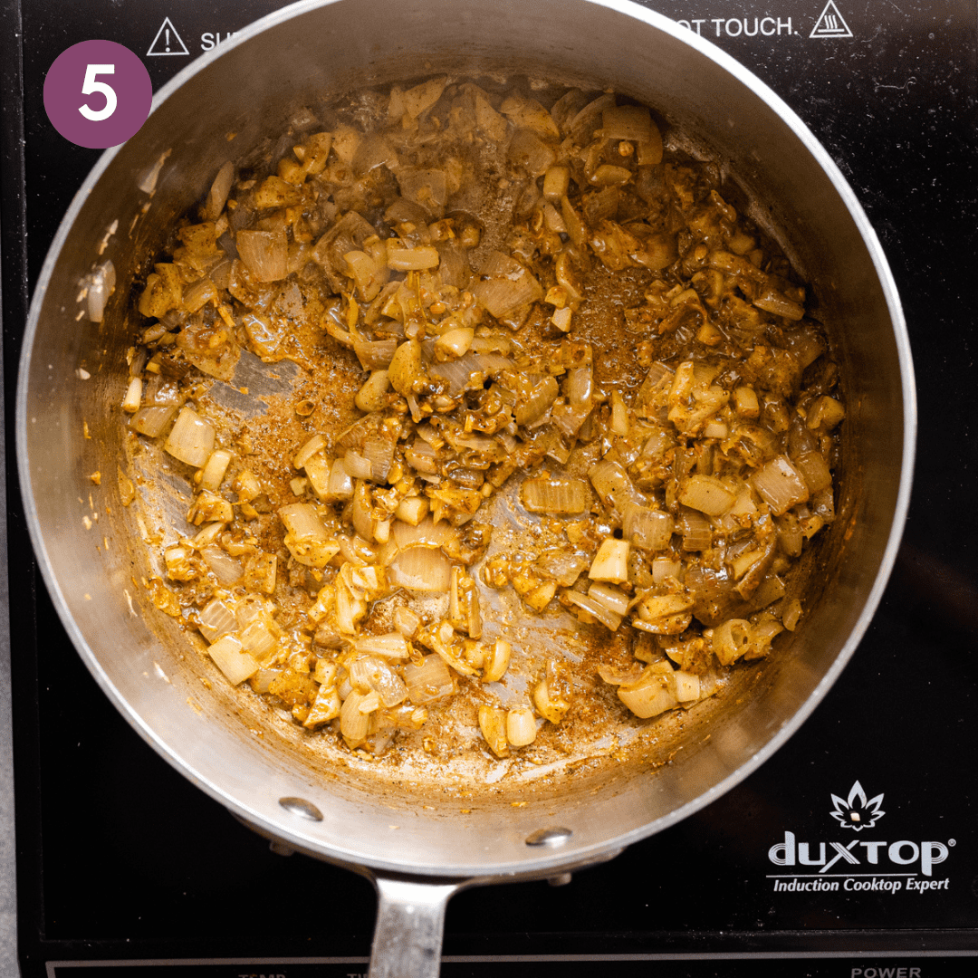 a golden mixture of sauteed shallots, garlic, ginger, lemongrass and spices in a stainless steel saucepan.