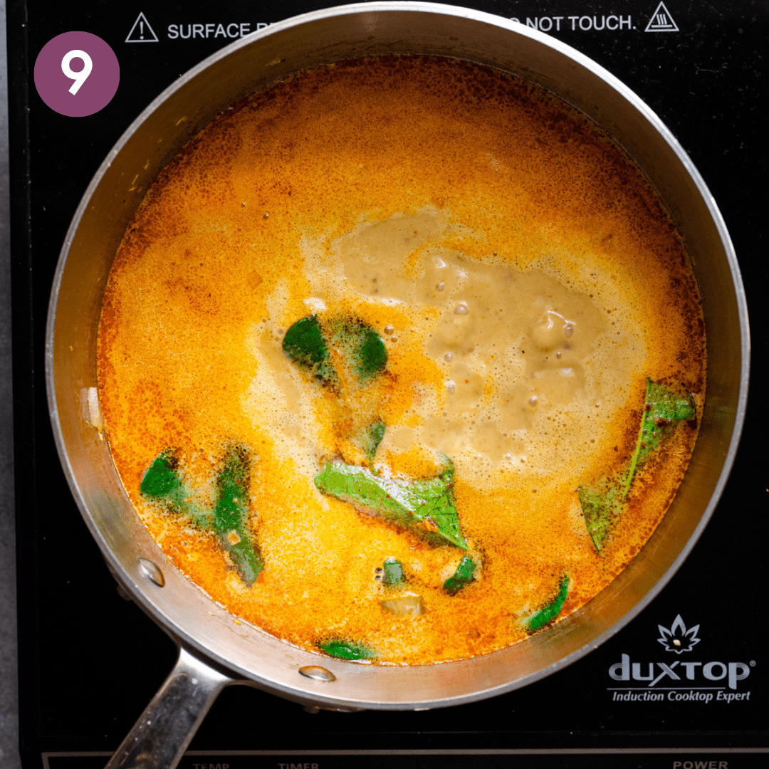 a golden coconut milk soup simmering in a stainless steel saucepan. 