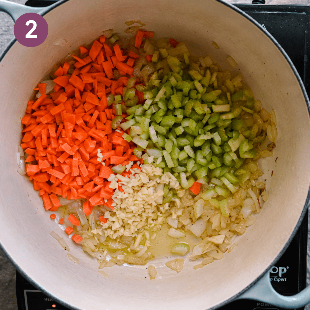 diced carrots and celery sitting on top of sauteed golden onions in a dutch oven. 