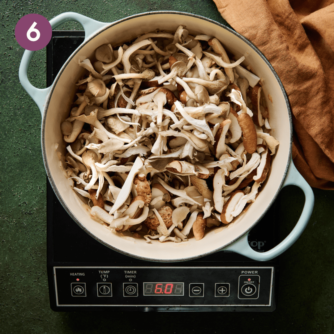 a big pile of sliced and torn mushrooms sitting in a light blue dutch oven.