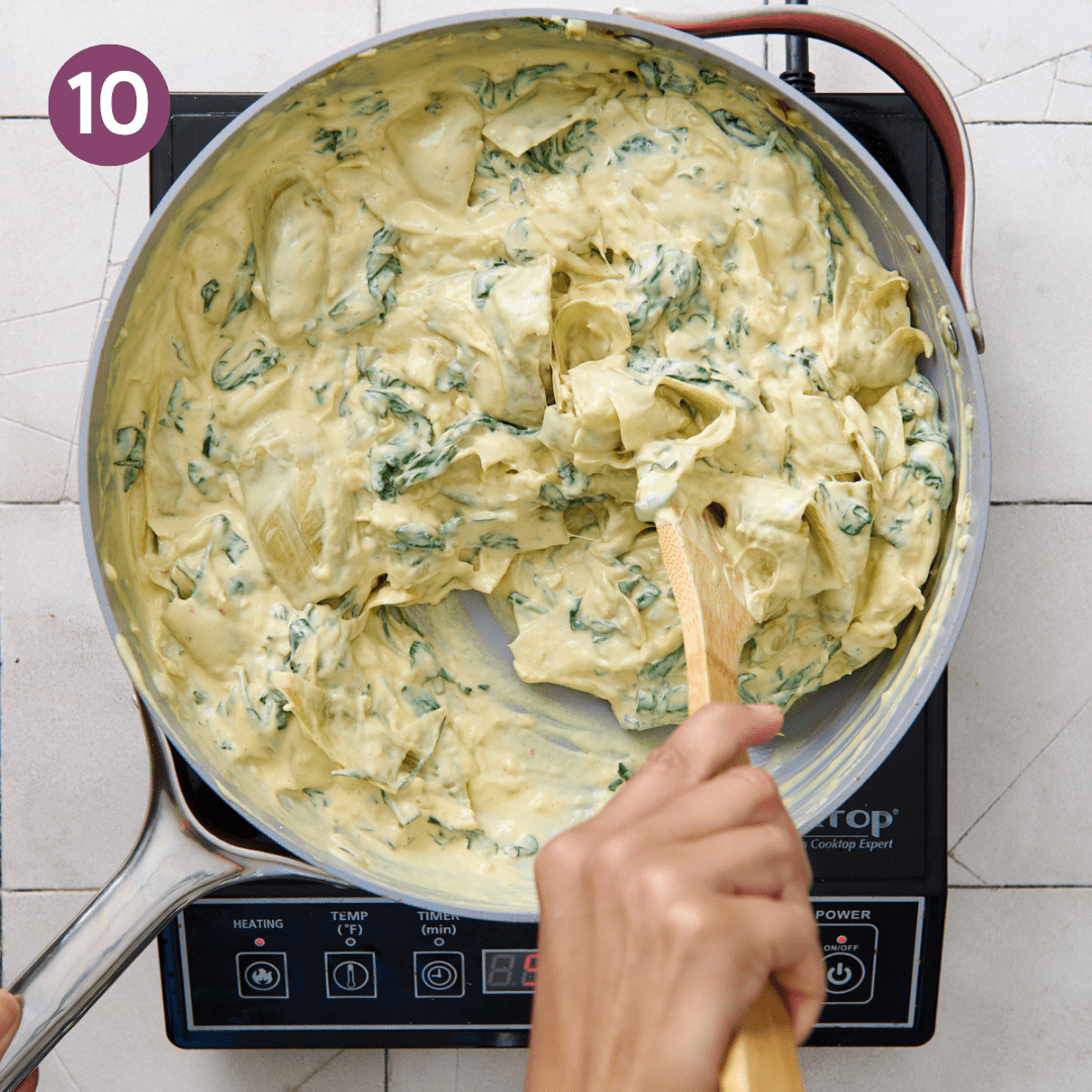 Woman stirring artichoke dip with a wooden spoon.