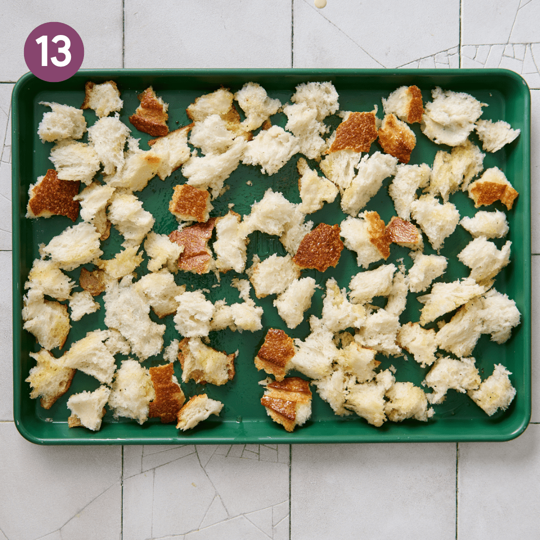 Seasoned bread pieces in an even layer on a sheet pan.