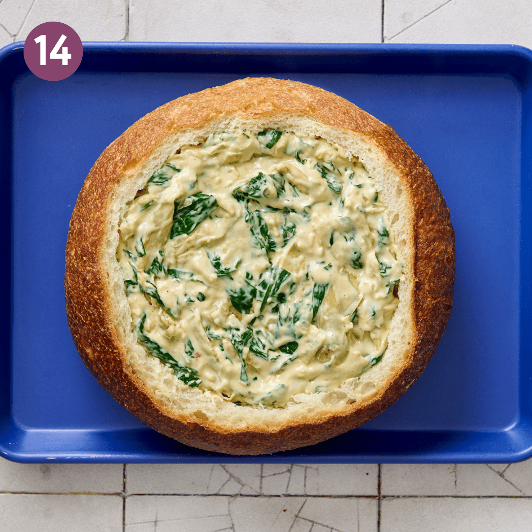 Bread bowl filled with spinach artichoke dip before being cooked.