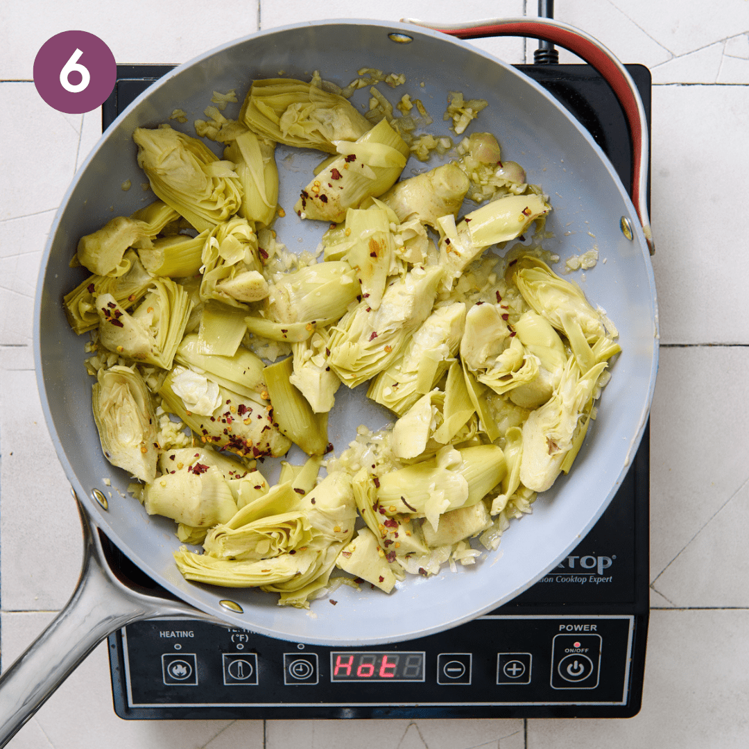 Artichokes and red pepper flakes added to aromatics in pan.